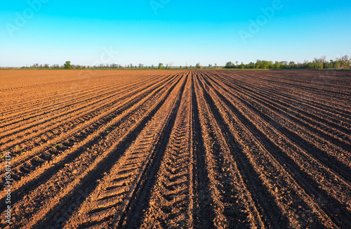 Preparing field for planting. Plowed soil  in spring time with blue sky.