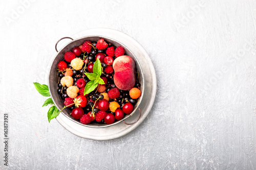 Mix fruit and berries in grey metal bowl. Top view.