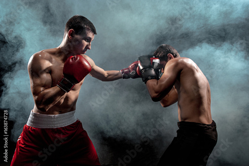 Two professional boxer boxing on black smoky background, © master1305