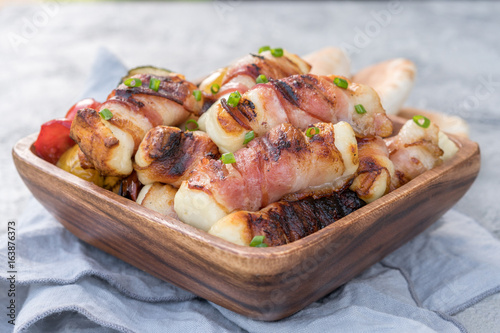 Grilled bacon wrapped haloumi cheese with vegetables and pita photo