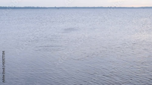 Stone skipping on water surface. Beautiful view of throwing a small flattened rock bouncing off water surface across body of water many times