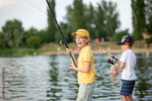 Two boys are fishing on the beach at sunset