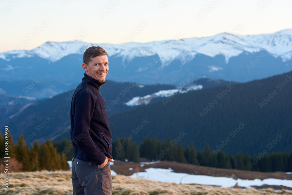 Portrait of happy man tourist in the evening. On the background beautiful panorama of snow-covered mountains