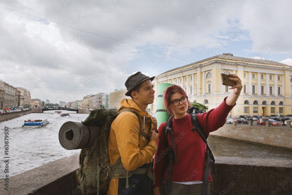 A couple of tourists taking selfies against the background of architecture