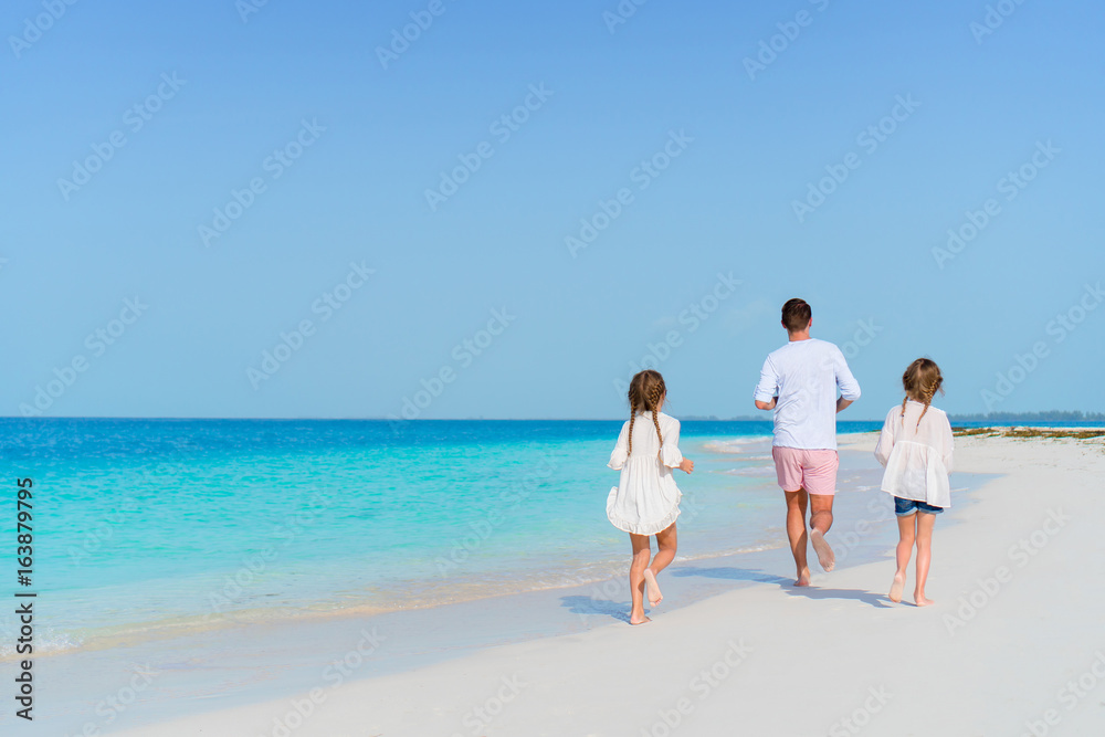 Family on white tropical beach have a lot of fun. Father and kids enjoy holidays on the seashore. Beach vacation activity Family on white tropical beach have a lot of fun. Father and kids enjoy holidays on the seashore. Beach vacation activity