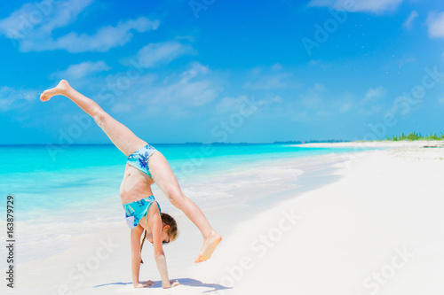 Active little girl at beach having a lot of fun. Sporty kid making the wheel on the seashore © travnikovstudio