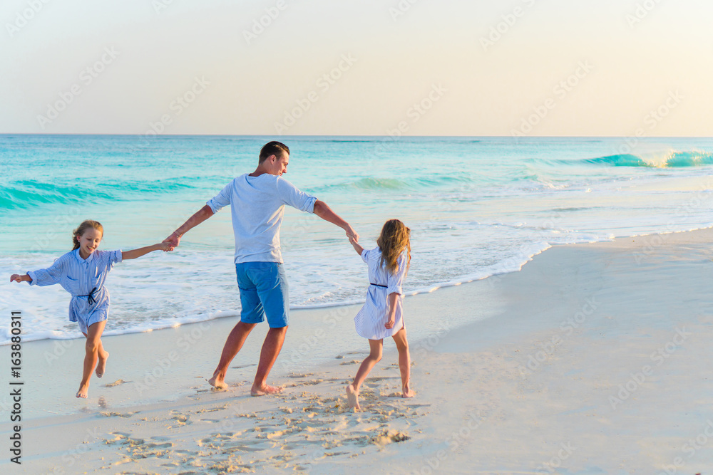 Family of dad and kids walking on white tropical beach on caribbean island