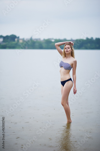 Portrait of a beautiful bikini model standing and posing in the water.