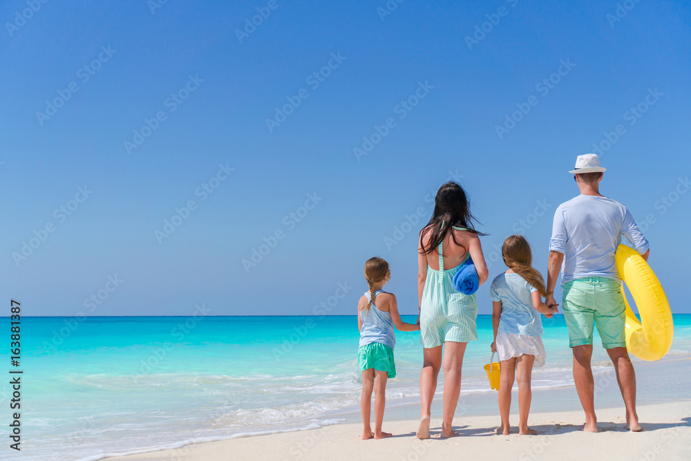 Happy beautiful family of four on a tropical beach. Parents and kids background seashore