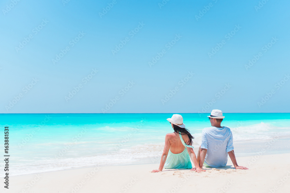 Young couple on white beach during summer vacation. Happy lovers enjoy their honeymoon. Family beach vacation