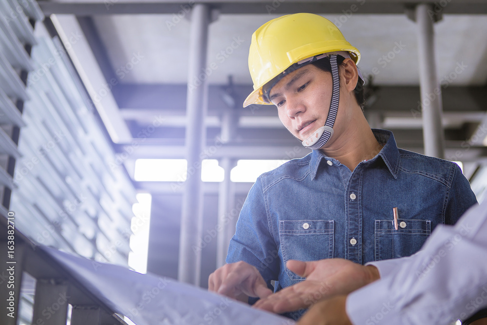 contractor and engineer with blueprints discuss at a modern construction site, Architecture and Engineering concept. close up contractor and engineer with blueprints discuss at a modern construction site, Architecture and Engineering concept. close up