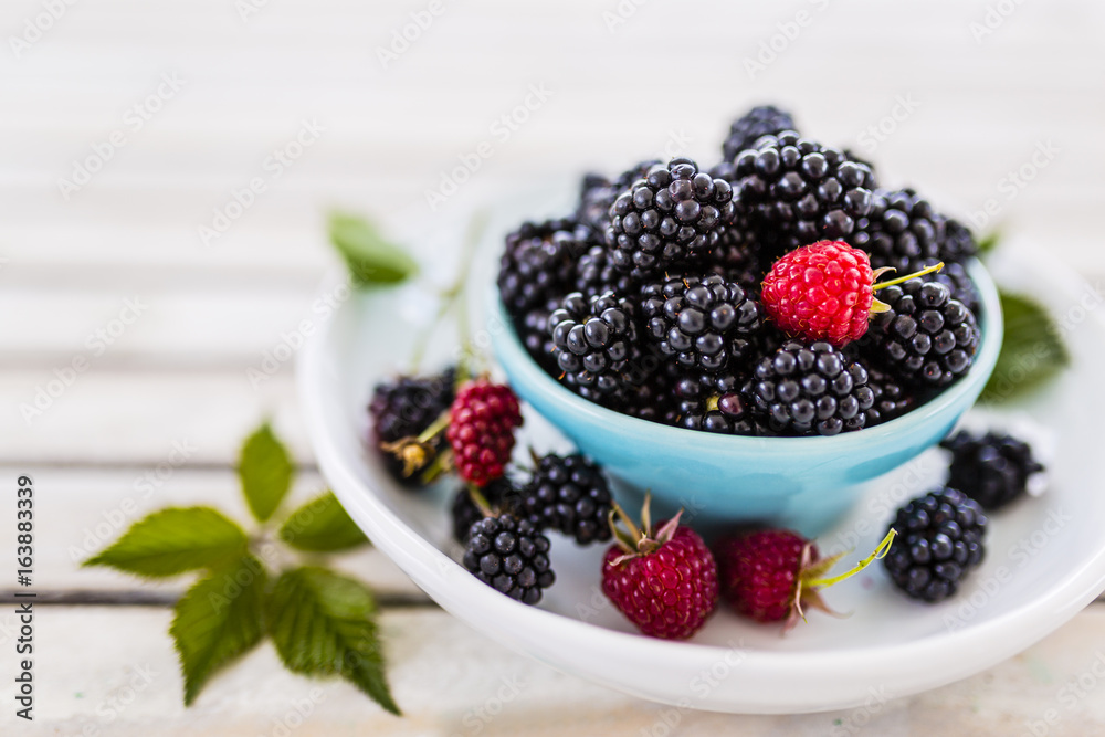 Fresh blackberries in bowl on wooden table in the garden. Fresh blackberries in bowl on wooden table in the garden.