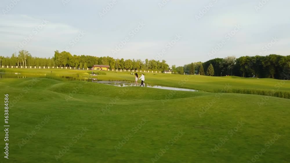 Aerial View Of Young Couple Walking In Summer Park, Circling Drone Shooting Man And Woman Outdoors Aerial View Of Young Couple Walking In Summer Park, Circling Drone Shooting Man And Woman Outdoors