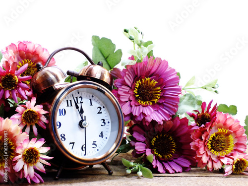 spring time with alarm clock and artificial flowers bouquet background