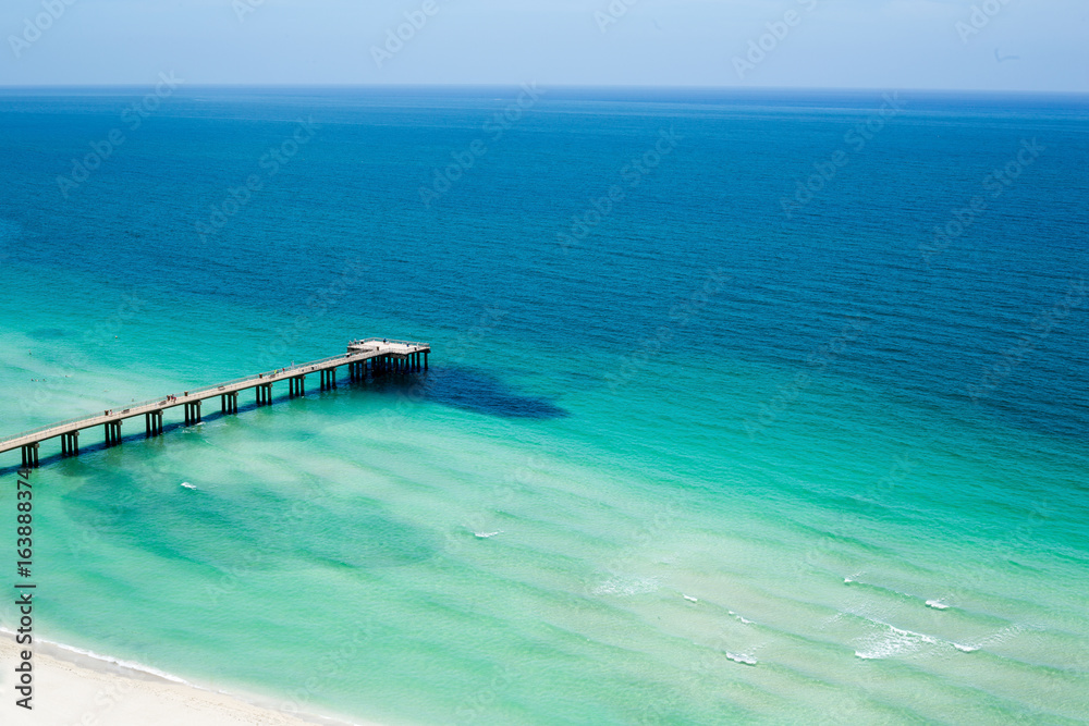 Pier jutting out into the ocean under clear blue skies