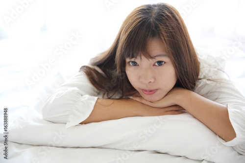 Asian young woman wake up with pillow in white room © Oran Tantapakul