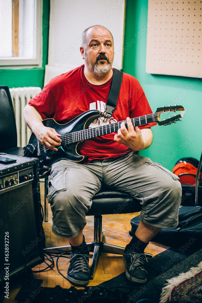 Obraz premium Behind scene. Guitarist practice playing guitar in messy music studio