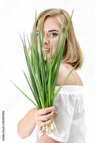 Portrait of Beautiful blond woman holding green onion on white background. Health and vitamins