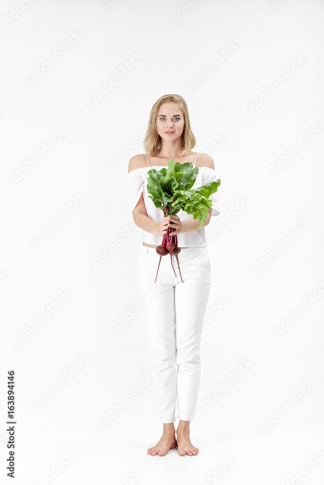Beautiful blond woman holds beetroot with green leaves on white background. Health and vitamins Beautiful blond woman holds beetroot with green leaves on white background. Health and vitamins