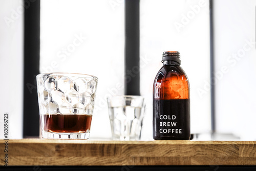 Billede på lærred Filter cold brew coffee bottle and glass on a wooden table