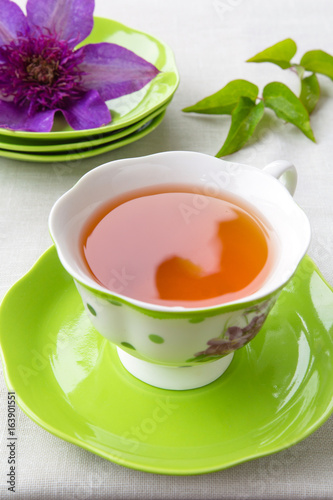 Tea in a cup of green and a bud of clematis colors in a rural style on a light background with a copy space