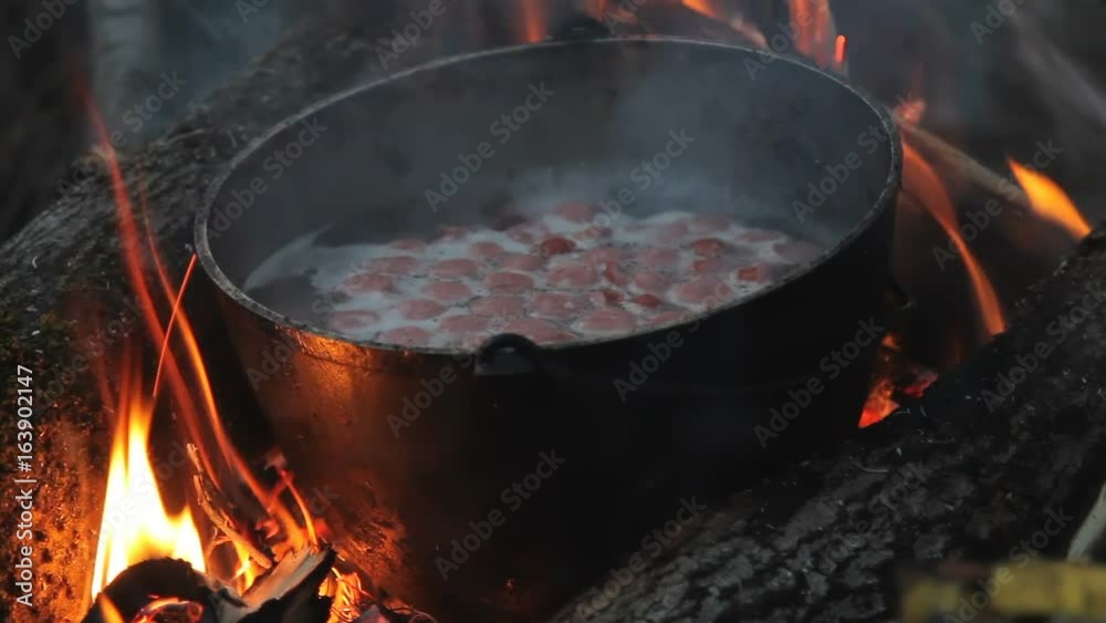 flame around the pot. in the evening to cook on the fire. in a pot standing on the fire boiling soup. Closeup flame around the pot. in the evening to cook on the fire. in a pot standing on the fire boiling soup. Closeup