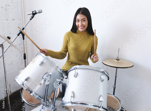 Teenage girls smiling while playing drum, happiness and enjoying music concepts.