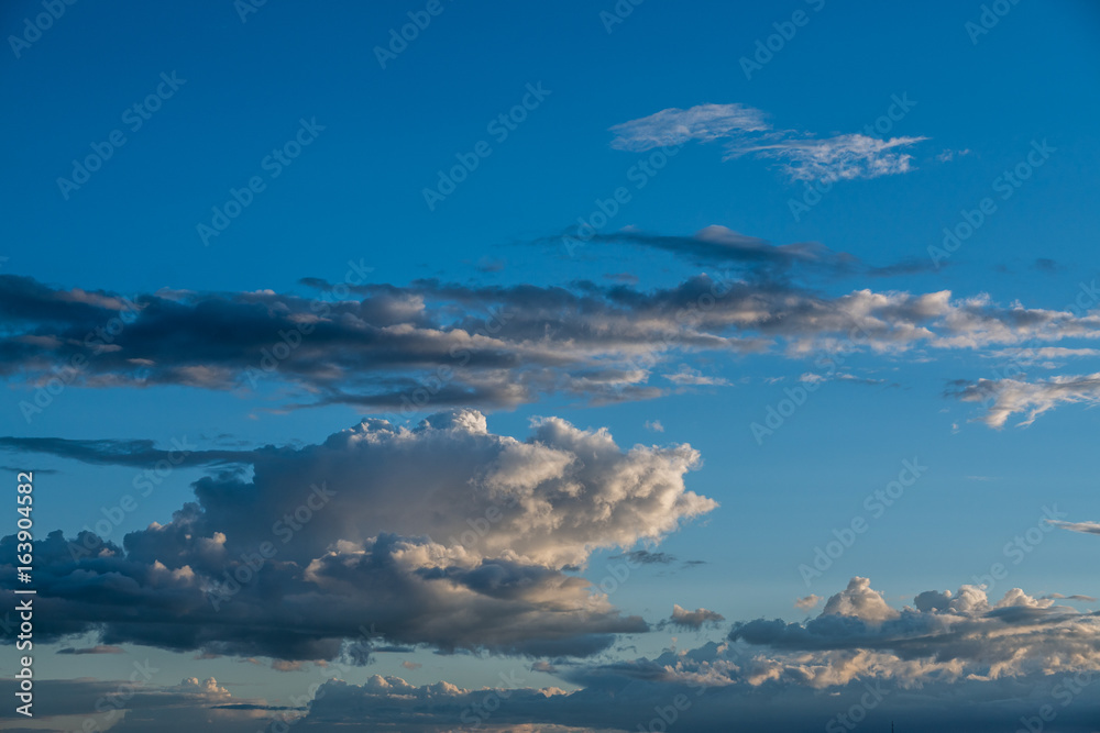 bright blue sky , puffy white clouds, sunset  