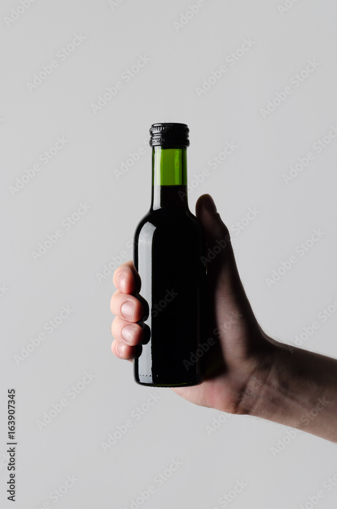 Wine Quarter / Mini Bottle Mock-Up - Male hands holding a wine bottle on a gray background Wine Quarter / Mini Bottle Mock-Up - Male hands holding a wine bottle on a gray background