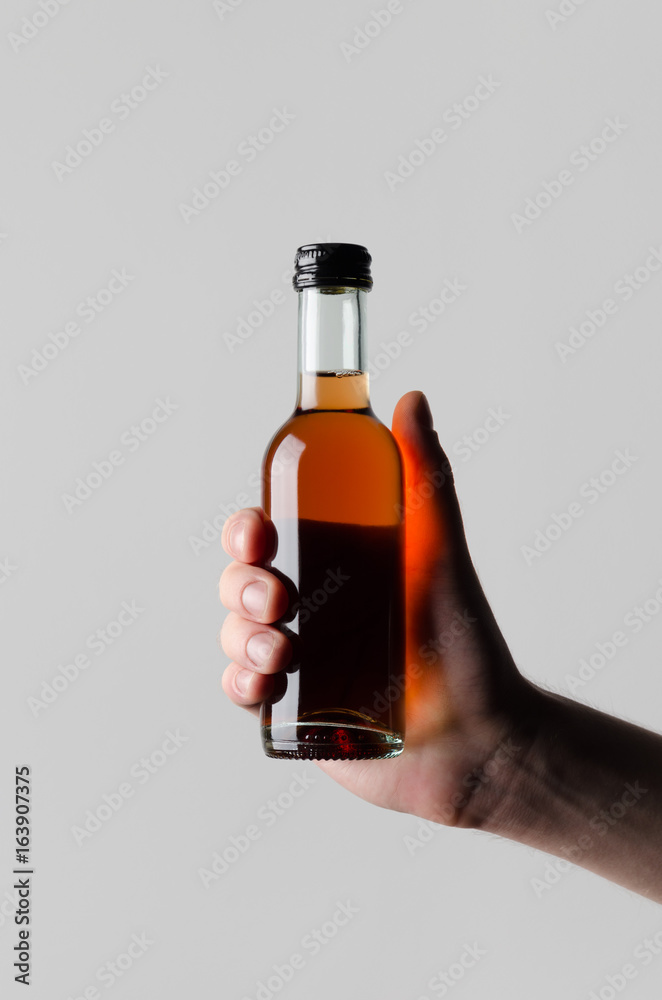 Wine Quarter / Mini Bottle Mock-Up - Male hands holding a wine bottle on a gray background Wine Quarter / Mini Bottle Mock-Up - Male hands holding a wine bottle on a gray background