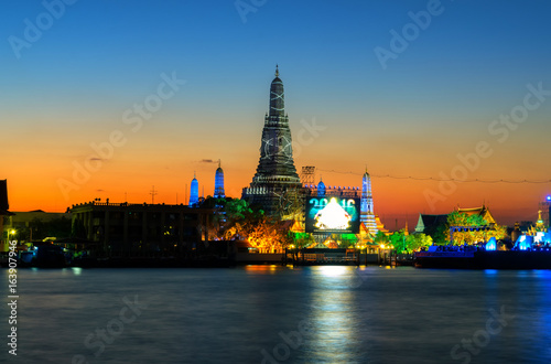 Wat Arun is a public facility, located on a river with evening light and light twilight in Thailand.