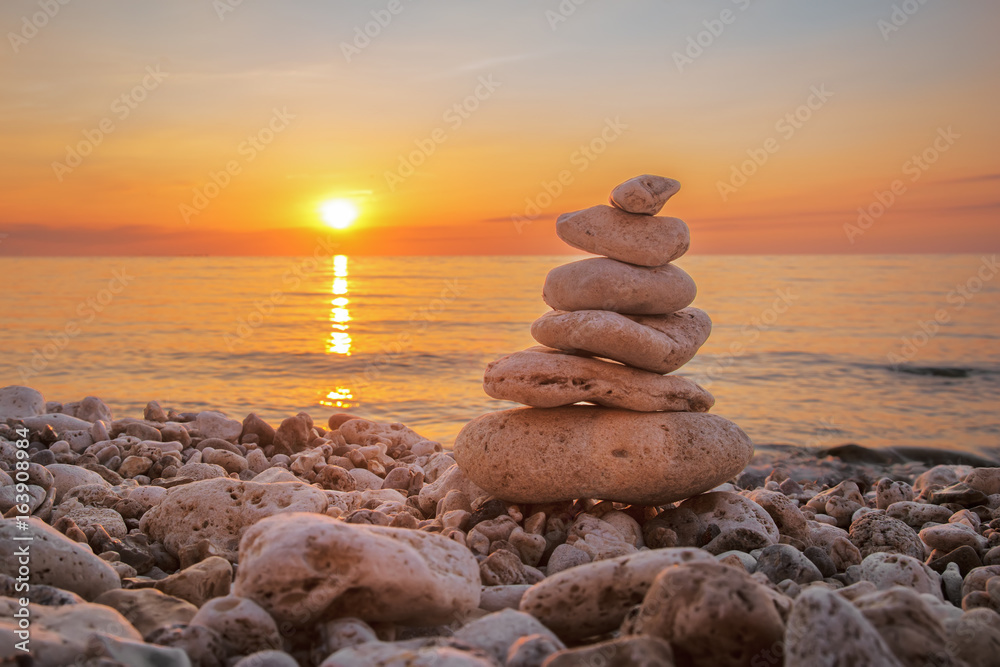 Fototapeta premium Pyramid of stones on the beach, beautiful sunset, sea landscape