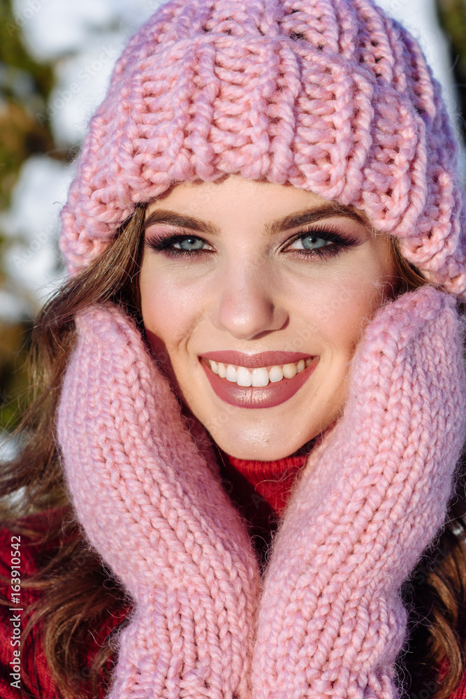 close up Winter portrait of a Happy candid beautiful young lady in a pink knitted beanie hat and gloves close up Winter portrait of a Happy candid beautiful young lady in a pink knitted beanie hat and gloves