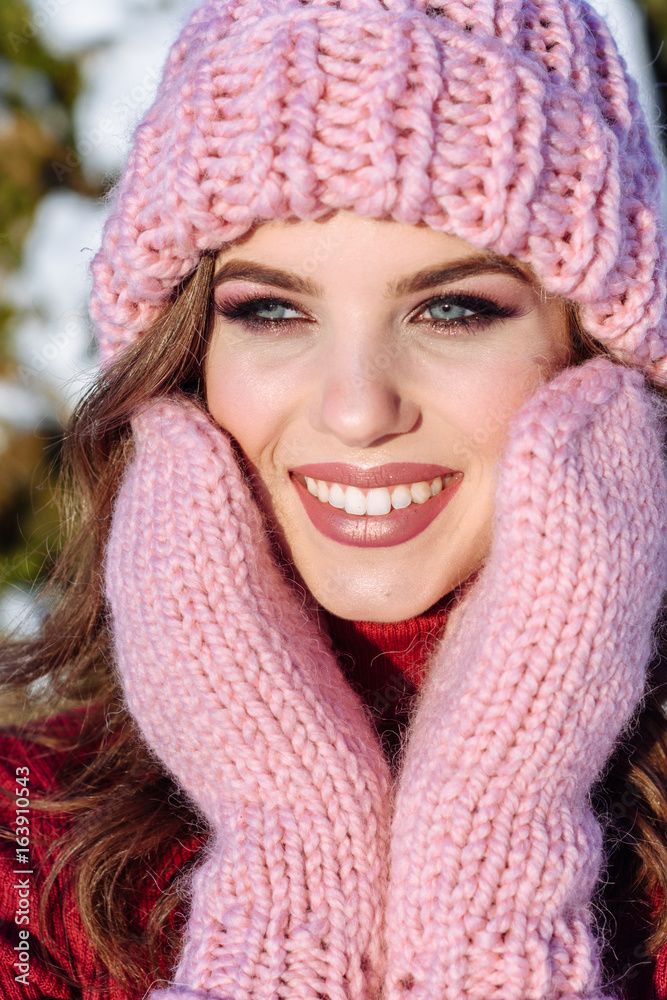 close up Winter portrait of a Happy candid beautiful young lady in a pink knitted beanie hat and gloves close up Winter portrait of a Happy candid beautiful young lady in a pink knitted beanie hat and gloves