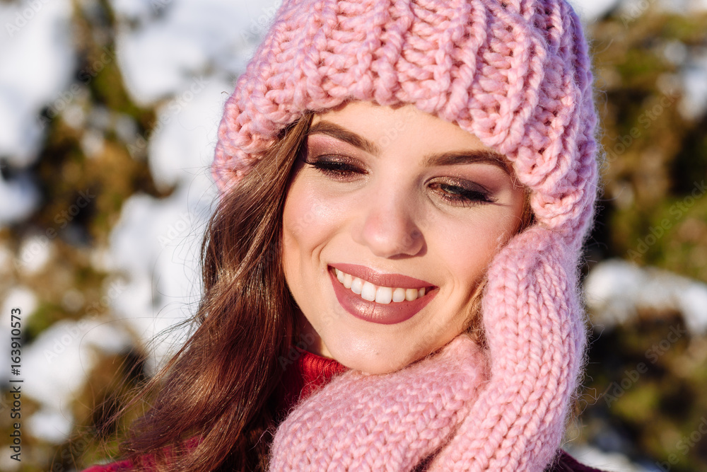 close up Winter portrait of a Happy candid beautiful young lady in a pink knitted beanie hat and gloves close up Winter portrait of a Happy candid beautiful young lady in a pink knitted beanie hat and gloves