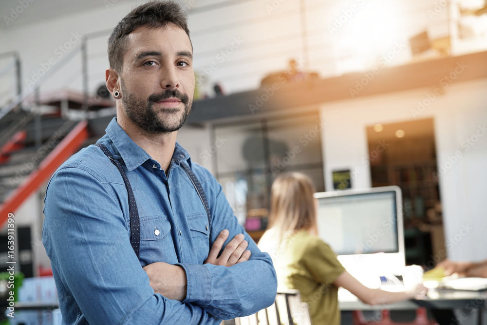 Fototapeta premium Modern guy in startup office with arms crossed