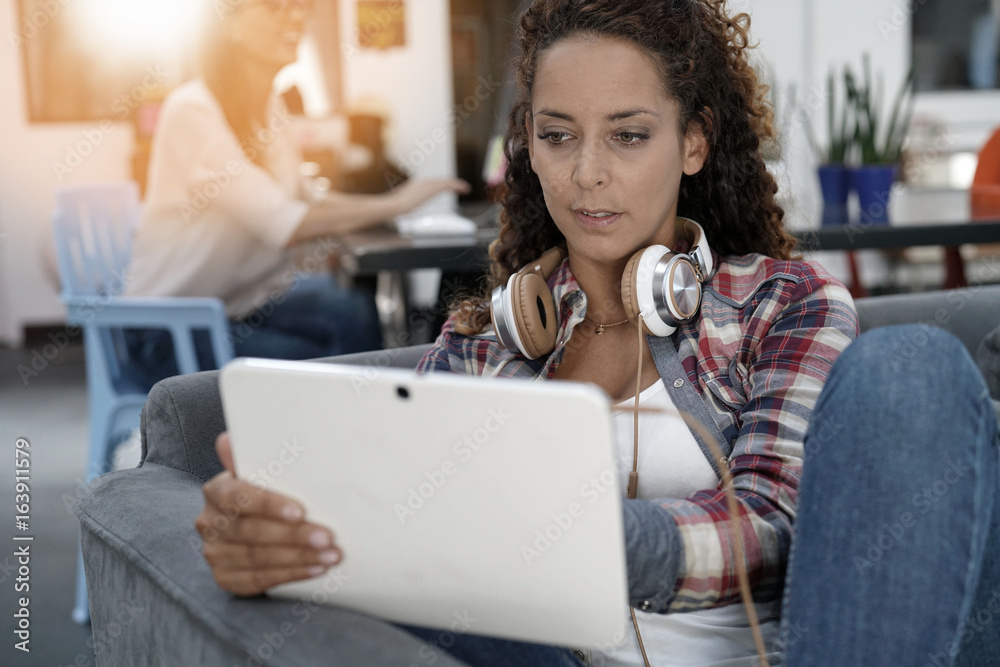 Trendy girl sitting in sofa with tablet and headphones Trendy girl sitting in sofa with tablet and headphones