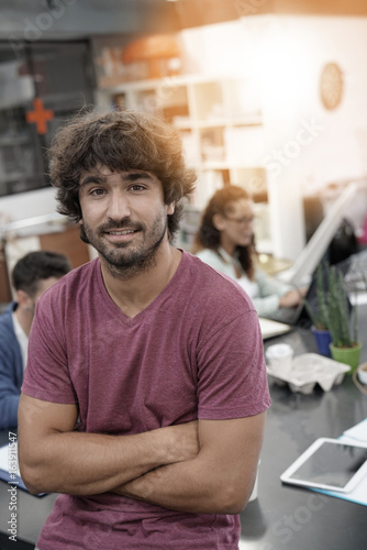 Trendy guy in coworking office with arms crossed