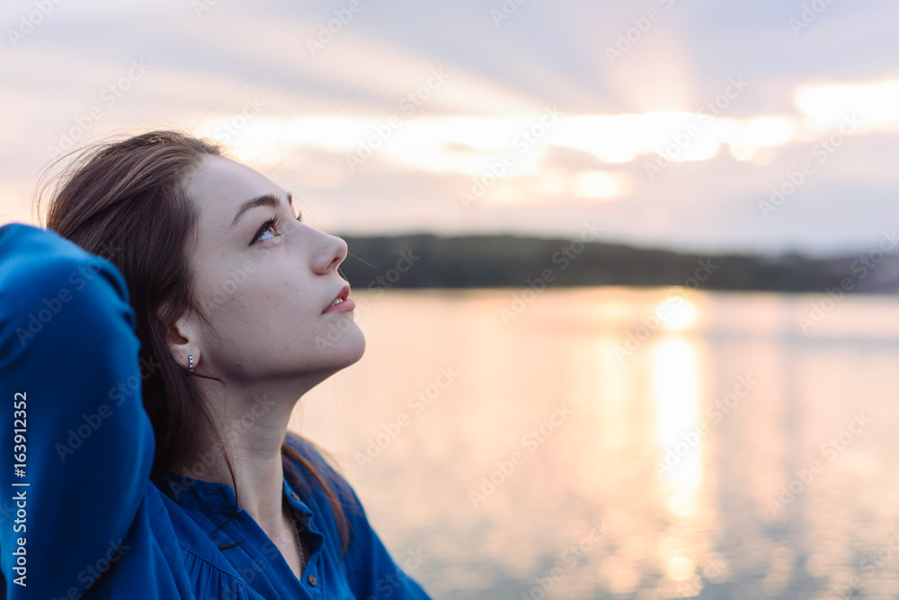 summer vacation happy portrait beautiful woman girl caucasian asian blended in blue shirt posing on background sky lake water sunset long hair brunette outdoors