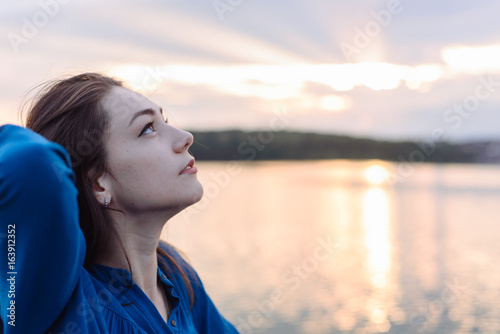 summer vacation happy portrait beautiful woman girl caucasian asian blended in blue shirt posing on background sky lake water sunset long hair brunette outdoors photo
