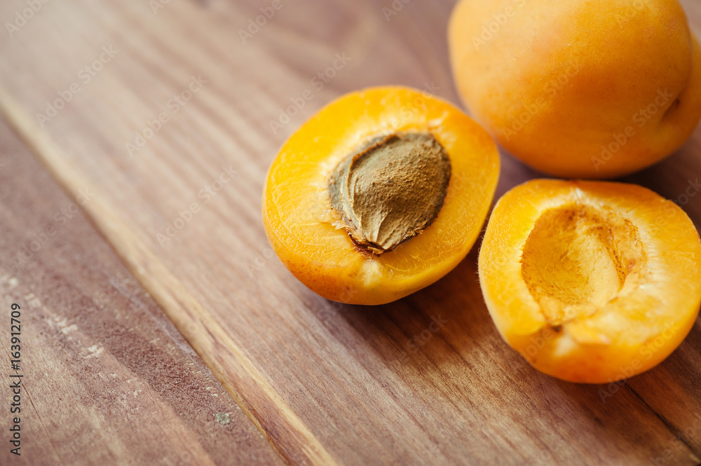 Delicious ripe apricots in a wooden bowl on the table close-up. Horizontal view from above