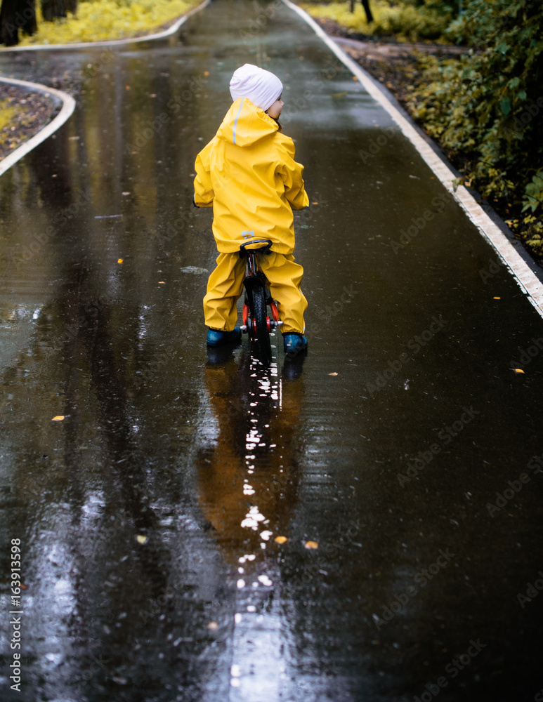 Little girl ride on bike in a rainy day Little girl ride on bike in a rainy day