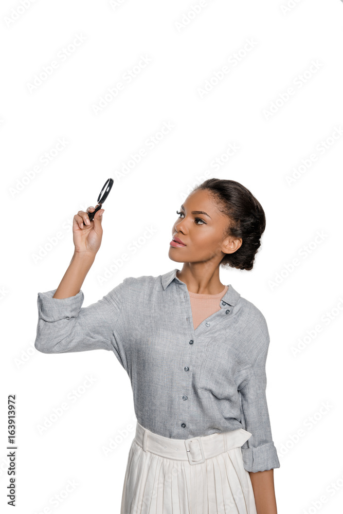 Attractive young african american woman looking at magnifier isolated on white Attractive young african american woman looking at magnifier isolated on white