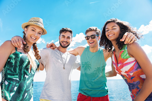 Happy youthful girls and guys relaxing on summer beach