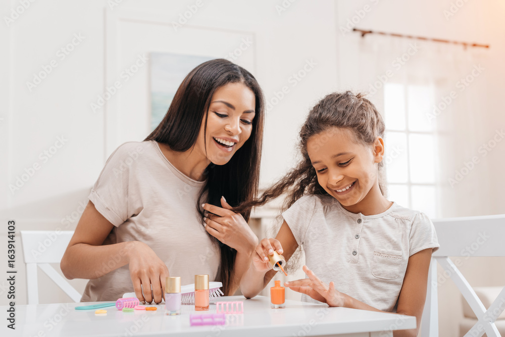 african american mother looking at happy daughter doing manicure at home african american mother looking at happy daughter doing manicure at home