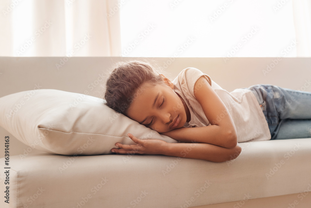 Adorable little african american girl sleeping on sofa at home Adorable little african american girl sleeping on sofa at home