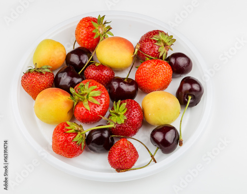 Tasty bright ripe strawberry, cherry and apricots on a white background