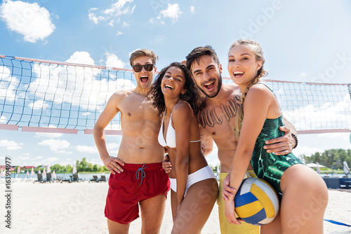 Cheerful young men and women having active rest on beach © Yakobchuk Olena