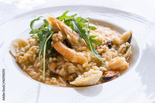 Tasty risotto with Shrimp, fresh herbs vegetables on a white plate