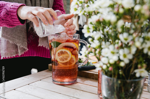 Jug of fruity mixed drink being prepared by woman
